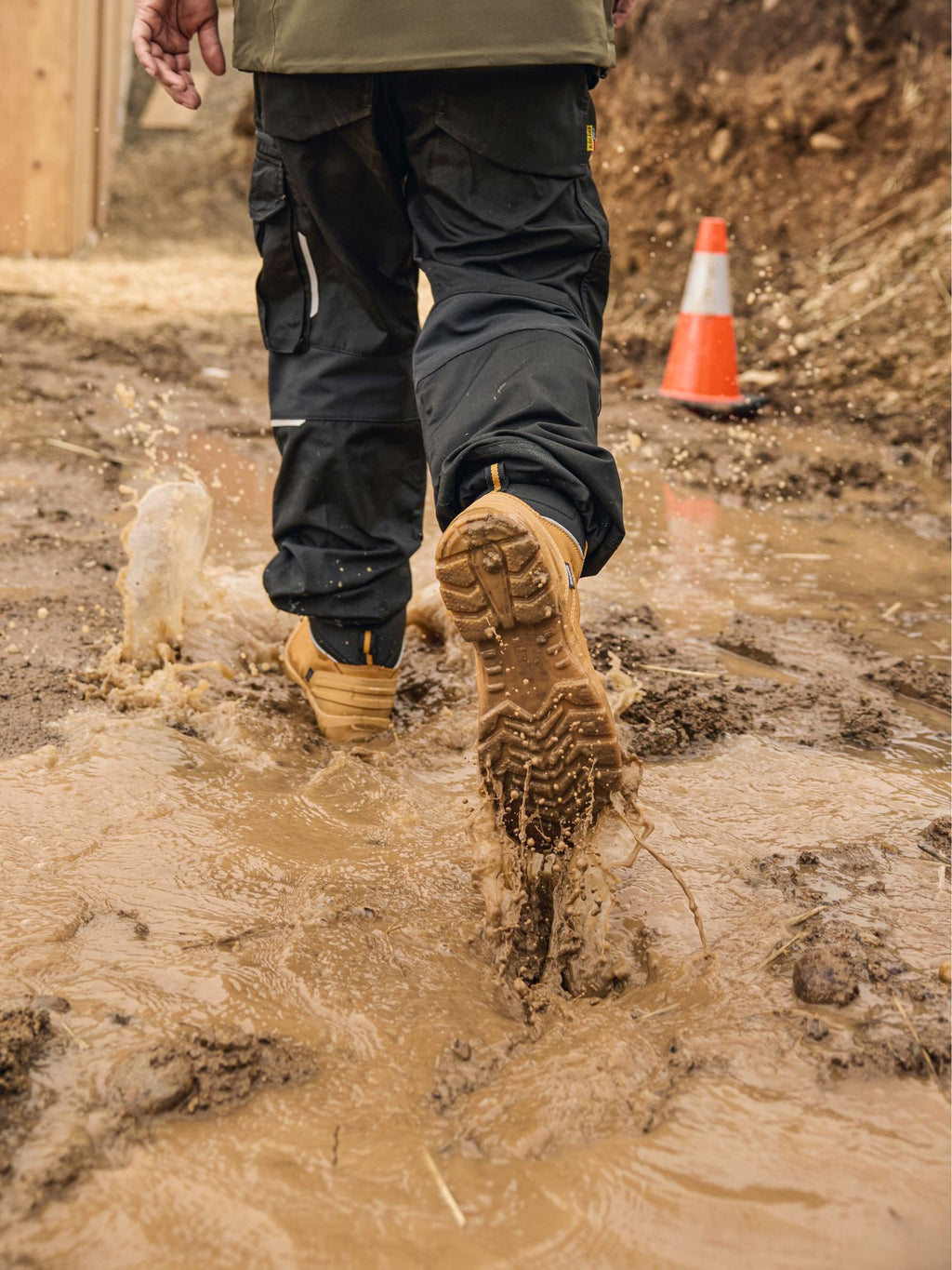 Tradesman walking through muddy jobsite in Blaklader 6 Inch Freelock Safety Boots in wheat