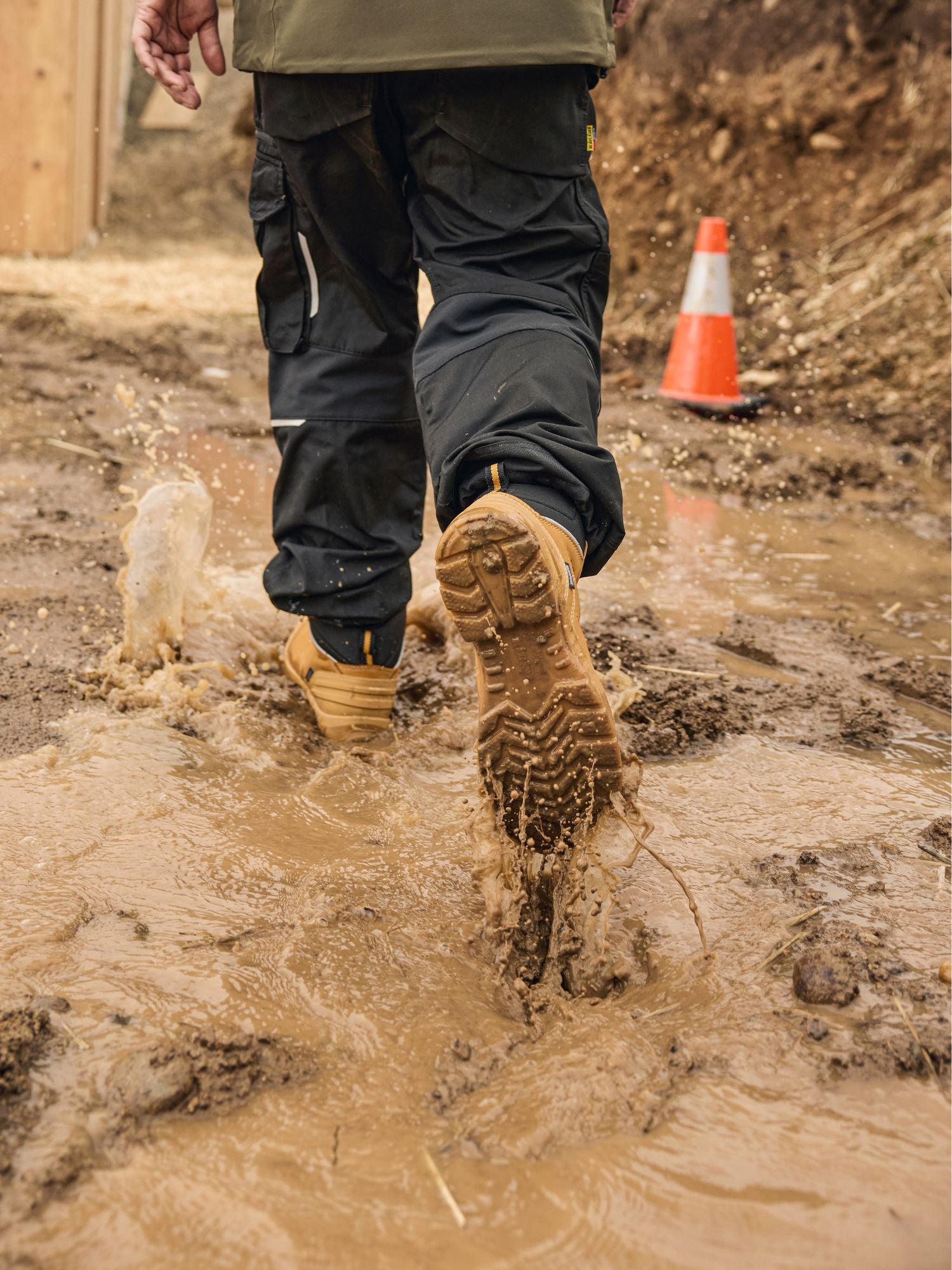 Tradesman walking through muddy jobsite in Blaklader 6 Inch Freelock Safety Boots in wheat