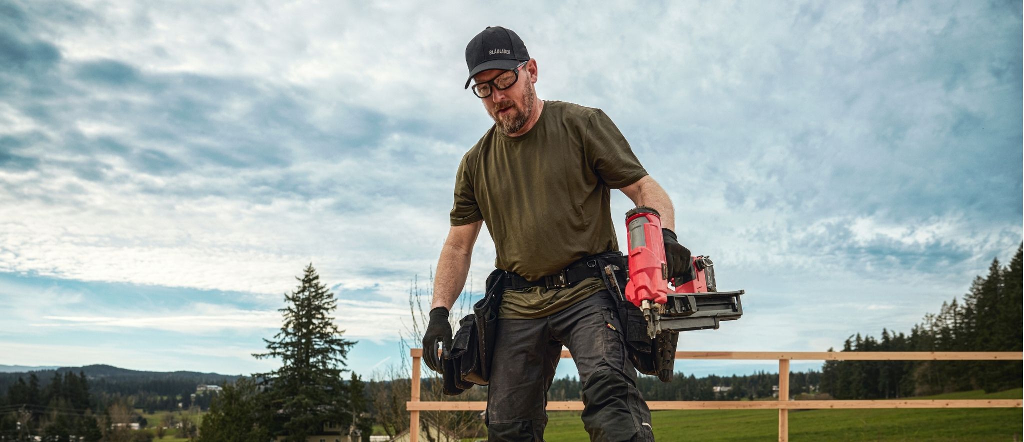 Blaklader Performance T-Shirt in Forest Night worn by tradesperson carrying nail gun on outdoor framing job site