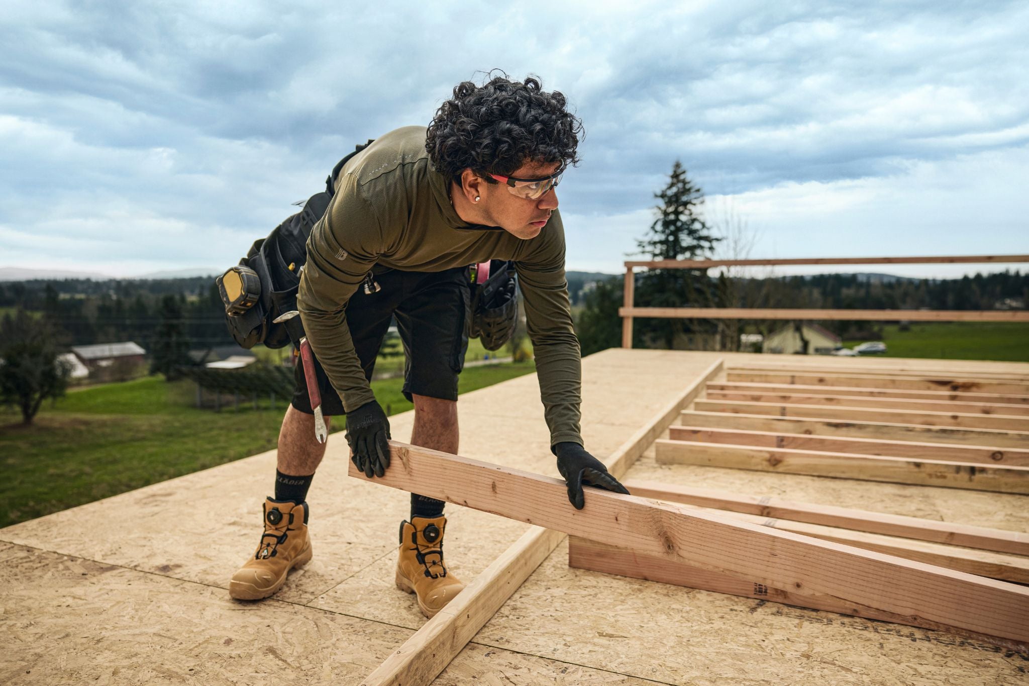 Blaklader Performance Hoodie in Forest Night and Service Shorts with Stretch in Black worn by carpenter framing roof on job site
