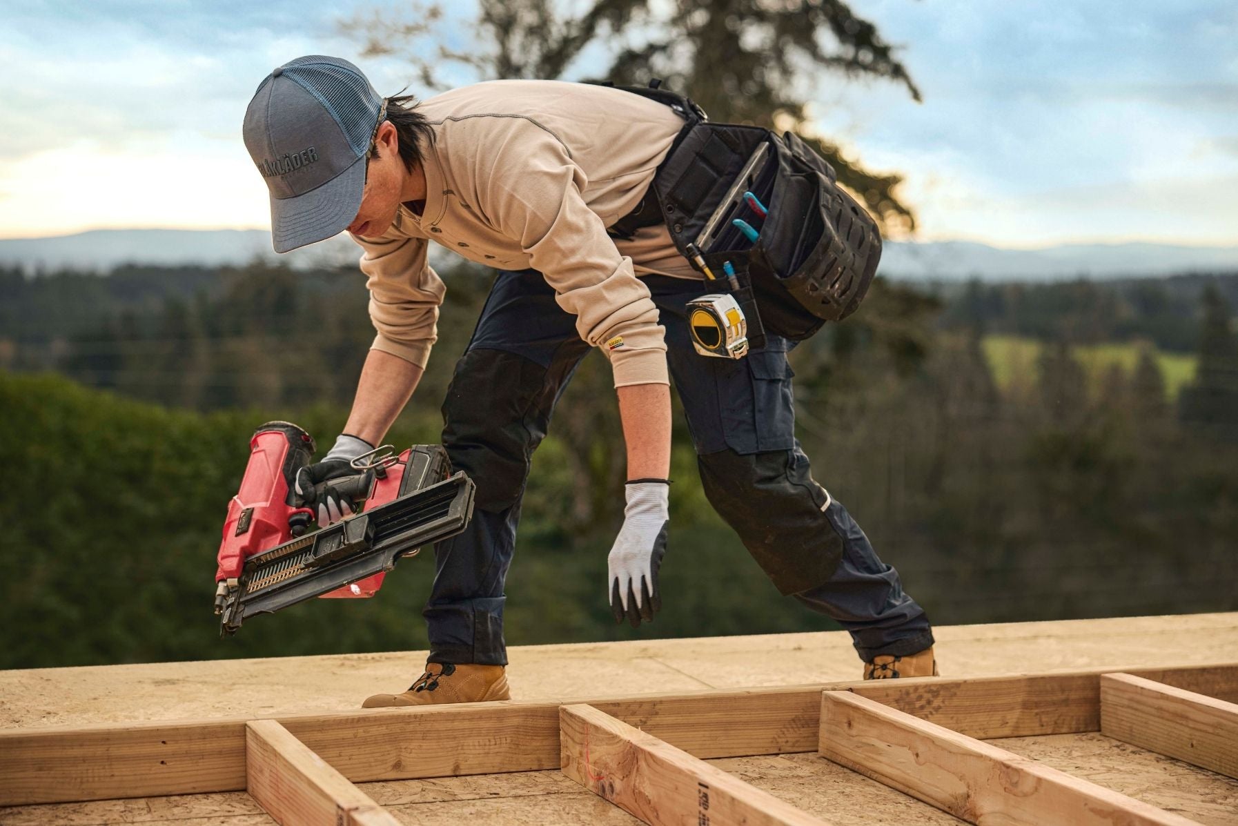 Blaklader Women's Ripstop Pants in Navy worn by female carpenter using nail gun on roof frame job site