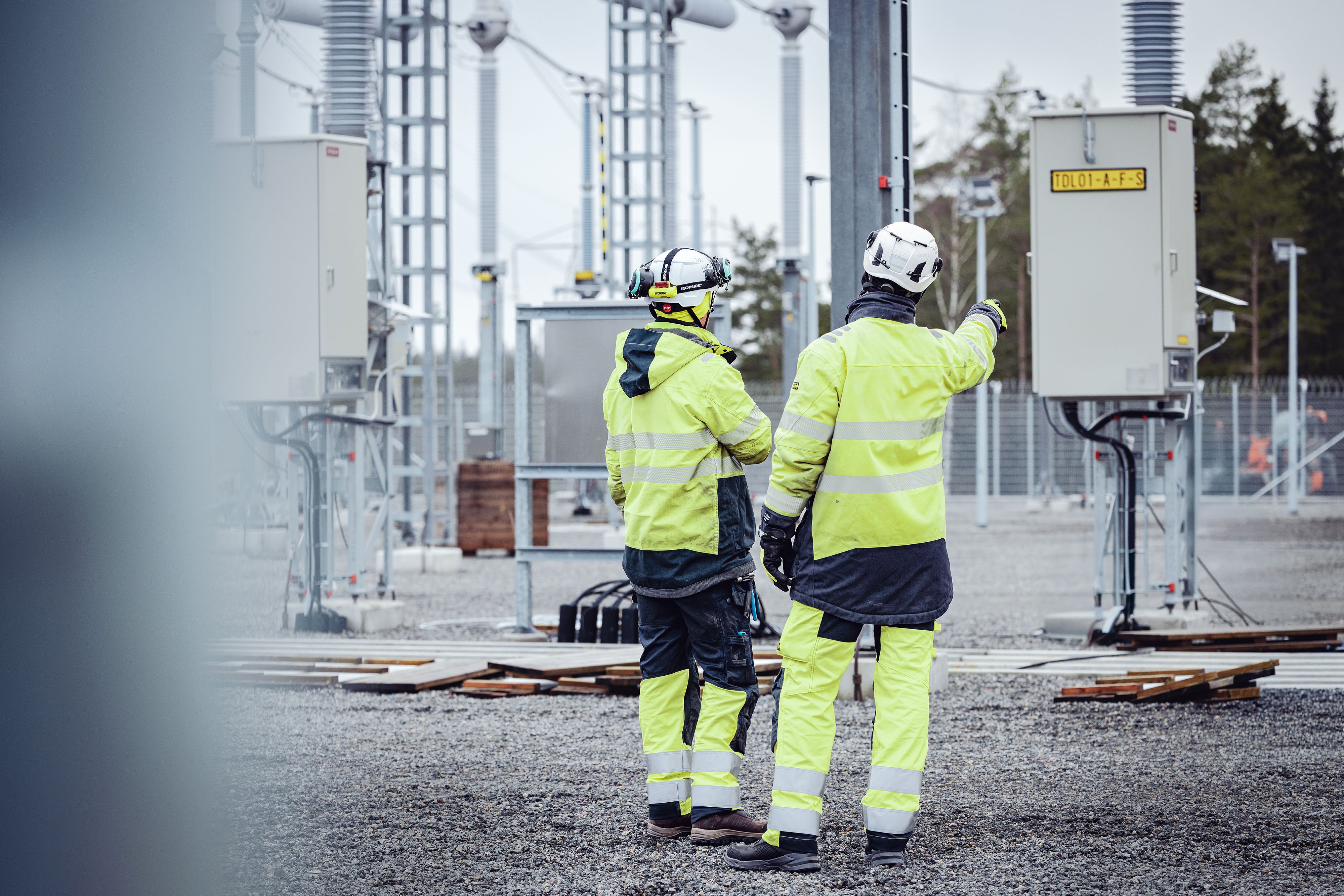 Two workers in high-visibility clothing and hard hats at a construction site.