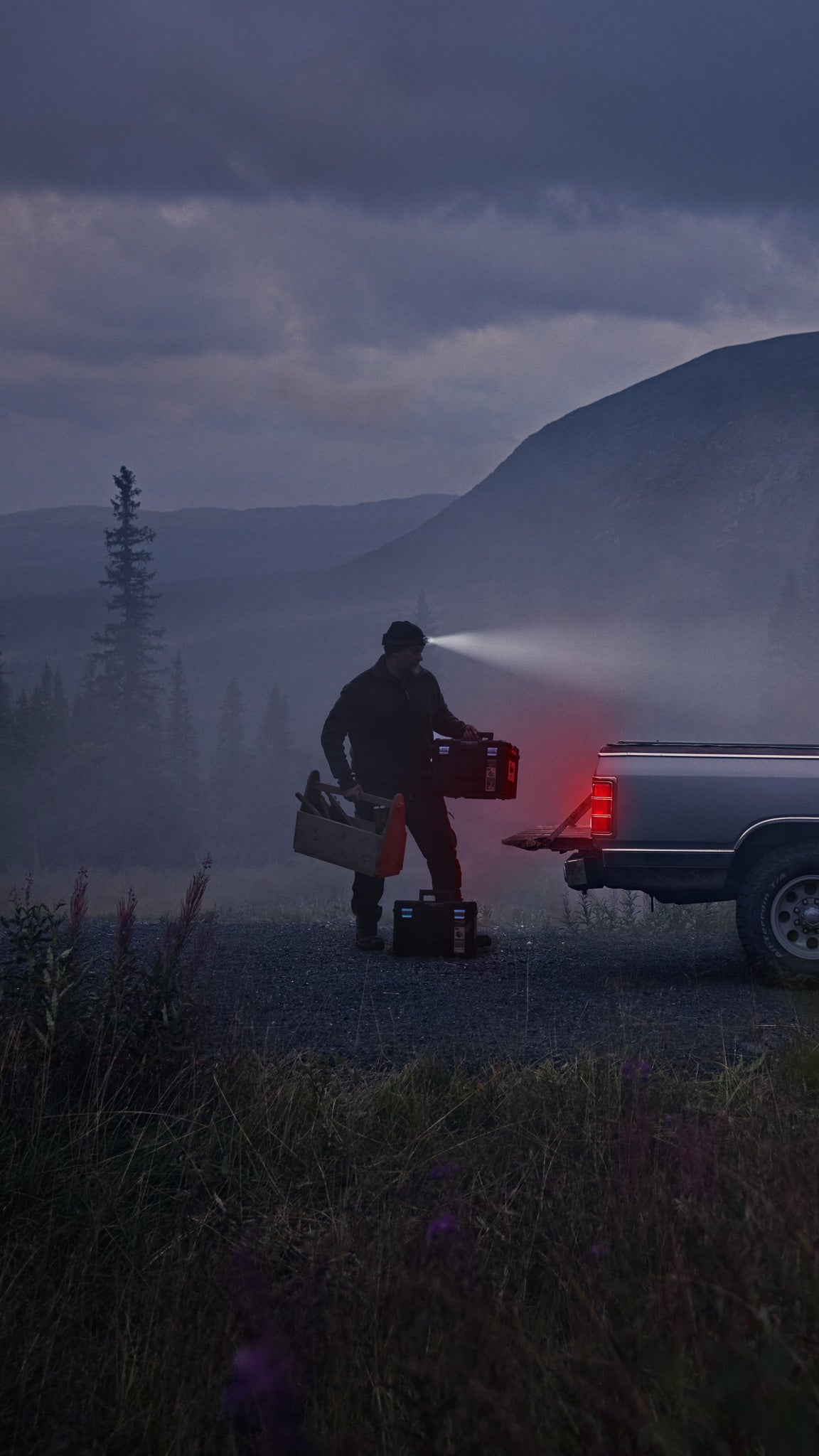 a tradesman loading his truck early morning wearing workwear with many tools