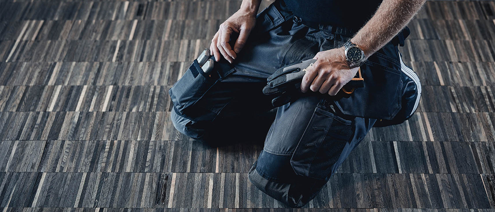 Person sitting on a wooden floor with a backpack and tools.